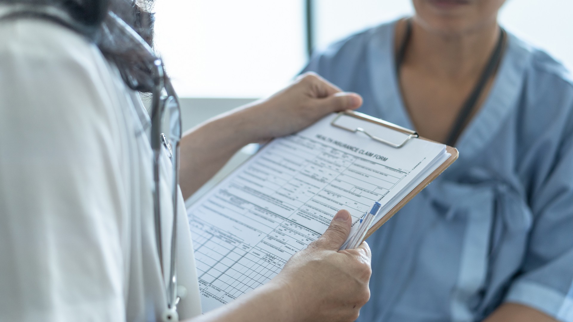 Formulário da reivindicação do seguro de saúde paciente nas mãos do doutor ou da enfermeira para a cobertura do medicare e o tratamento médico da doença, ferimento do acidente e admitido na divisão do hospital